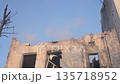 fire accident, Disaster zone, Public safety. Firefighter sprays water on ruins of heavily damaged building, showing destruction, fire aftermath, and urban conflict impact. 135718952