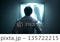 Doctor examining a glowing chest X-ray in a dark room for medical diagnosis. 135722215