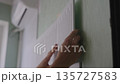 Hands applying acoustic panel to wall, soundproofing room, reducing noise, installing black and white sound absorbing material, improving studio or home acoustics, close-up. Shooting in slow motion. 135727583