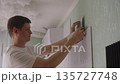 Side view of focused man applying decorative mirror panels to textured wall, creating new focal point and modern aesthetic in home improvement project through careful diy installation, slow motion. 135727748