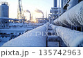 Frosty pipelines in an industrial facility during early morning in a cold environment with rising sun in the background 135742963