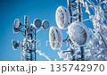Frozen technology on a bright winter day with ice-covered communication towers shining against a clear blue sky 135742970