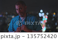 Tired male doctor standing against city lights at night 135752420