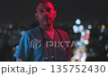Tired male doctor standing against city lights at night 135752430