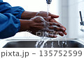 Person Washing Hands with Soap Under Faucet in Sink for Health and Hygiene. 135752599