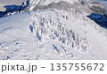 Cinematic aerial view of snowy mountain ridge with frozen trees and long shadows, Europe. 135755672