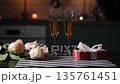 A man sets a gift box alongside a card that says Happy Valentines Day. There are glasses of champagne and a bouquet of roses on the table in a kitchen 135761451