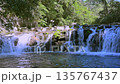 multiple waterfalls falling over a bare rock into a rapid flowing mountain stream 135767437