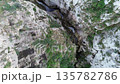 Aerial drone footage flying above a dramatic rocky canyon with steep limestone cliffs and a narrow 135782786
