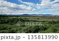 Wide scenic view of green field with distant mountains and blue sky, beautiful natural landscape, environment concept. 135813990