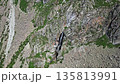 Aerial view of a waterfall cascading down a rocky mountain. Nature landscape with water stream, erosion, and green vegetation. 135813991