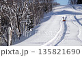 A young girl climbs a snow-covered mountain and pulls a tubing behind her. Winter outdoor recreation 135821690