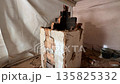 demolition of an old heating stove in an emergency state with signs of wear. cracks in the brickwork and soot stains. a hole for the chimney in the ceiling. demolition of an old heating stove in an emergency state with signs of wear. cracks in the brickwork and soot stains. a hole for the chimney in the ceiling. 135825332