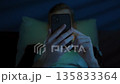 Man lying in bed at night, holding mobile phone. Social media addiction 135833364