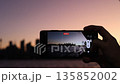 スマホ画面に映るシドニーのビル街の夕焼けシルエット スマホ画面に映るシドニーのビル街の夕焼けシルエット 135852002