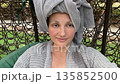 Relaxing spa day woman with towel on her head swinging on a swing and taking selfies, joy, peace, tranquility portrait 135852500