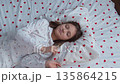A girl in heart-patterned pajamas lies down on a pillow and falls asleep soundly. High quality 4k footage 135864215