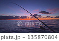 Offshore bottom fishing at sunset from boat with rod over calm sea 135870804