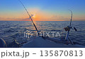 Offshore trolling fishing at sunset with rods on boat in open sea 135870813