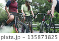 happy young asian cyclists chatting on roadside while training outdoors 135873825
