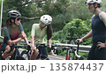 happy young asian cyclists chatting on roadside while training outdoors 135874437