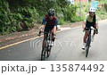 young asian cyclists man and woman riding bicycle outdoors on rural road 135874492