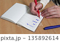 特寫鏡頭：一位女士的手正在筆記本上寫下她的行程。 135892614