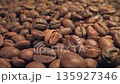 Roasting coffee beans process with smoke rising in slow motion from freshly roasted seeds on dark background, top view 135927346