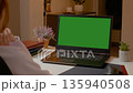 Woman working in home office with laptop and green screen setup 135940508