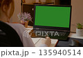 Woman working on laptop with green screen while taking notes in home office 135940514