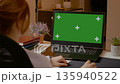 Woman working on laptop with green screen in home office during day 135940522
