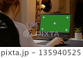 Woman focuses on tasks in a home office with green screen setup 135940525