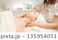 Woman receiving a professional chest and facial massage in a spa wellness center. 135954051