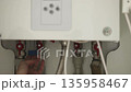 Female hand pointing to blue taps of the heating gas boiler for regulation of water pressure. 4K 135958467