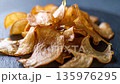 Caramelized root chips spiral from a stone plate as the camera pushes in,highlighting crisp textures 135976295