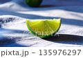 Sunlight hits a semicircle lime on wrinkled blue fabric as the camera orbits, a blurred whole lime 135976297