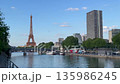 Eiffel Tower by the river at noon with boats and city buildings in Paris 135986245