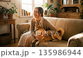 A beautiful woman laughing happily while petting a Shiba Inu on a sofa in a bright living room A beautiful woman laughing happily while petting a Shiba Inu on a sofa in a bright living room 135986944
