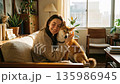 A beautiful smiling woman gently hugging her beloved Shiba Inu dog on a sofa in a sunny living room A beautiful smiling woman gently hugging her beloved Shiba Inu dog on a sofa in a sunny living room 135986945