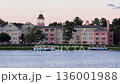 Pastel resort buildings stand along a calm lake while two tour boats cruise in front. Soft evening light creates a peaceful waterfront vacation scene in Orlando, Florida. 136001988