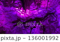 A dinosaur skeleton hangs along the rock wall under a purple lit ice cave ceiling. Jagged stalactites and glowing stone create a dramatic prehistoric atmosphere. 136001992