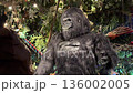 A large gorilla statue stands in a lush jungle theme restaurant. Artificial foliage and dramatic lighting create a playful rainforest animal scene. 136002005