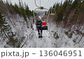 Man sitting on chairlift moving over snowy winter forest in mountains resort 136046951