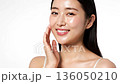 This is a portrait of a woman touching her moist, smooth skin in a brightly lit studio. 136050210