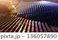 Aerial view of a massive solar energy field covering hills. Sunset light creates reflections and highlights across the photovoltaic array. 136057890