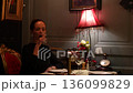 Woman with red wine alone at candlelit vintage restaurant table 136099829