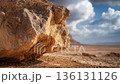 Close-up of a large rock formation in a desert landscape, showcasing detailed textures and colors under a dramatic sky with clouds and distant hills in the background 136131126