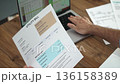 Mature man carefully reads details of utility bill inputting data into computer system, male accountant reviews summary of office expenses from printed documents slow motion 136158389