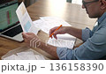 Middle-aged man reviews utility bill taking notes in paper notebook, male office worker calculates expenses related to office services preparing financial reports for company 136158390