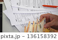 Businessman sitting at wooden table reconciles accounts by tallying 50-euro banknotes and reviewing tax paperwork pertained to household office expenses slow motion 136158392